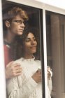 Задумчивая пара смотрит в окно дома — стоковое фото