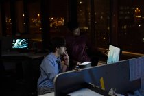 Executives working late at desk in office at night — Stock Photo