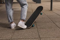 Sección baja de skateboarder femenino jugando con skateboard en la ciudad - foto de stock