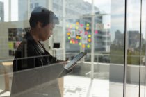 Vue latérale d'un dirigeant d'entreprise utilisant une tablette numérique au bureau . — Photo de stock