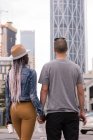 Вид ззаду пари тримає руки під час перетину вулиці в місті — стокове фото