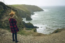 Vista posteriore della donna rossa in piedi vicino alla spiaggia in Irlanda . — Foto stock