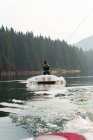 Atleta masculino adulto medio wakeboarding en agua de río - foto de stock