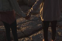 Unterteil des Paares hält Händchen, während es am Strand steht — Stockfoto