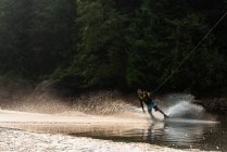 Atleta masculino adulto medio wakeboarding en agua de río - foto de stock