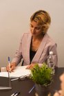 Weibliche Führungskräfte schreiben auf Notizblock im Büro — Stockfoto