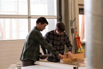 Two craftsmen discussing over wooden plank in workshop — Stock Photo