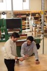 Two craftsmen discussing over digital tablet in workshop — Stock Photo