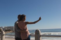 Романтическая пара делает селфи на набережной рядом с пляжем — стоковое фото