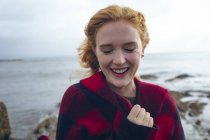 Рыжая женщина улыбается на пляже . — стоковое фото