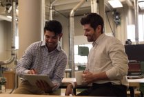 Zwei Handwerker diskutieren in Werkstatt über digitales Tablet — Stockfoto