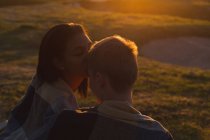 Casal beijando na praia durante o pôr do sol — Fotografia de Stock