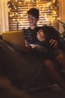 Пара використовує ноутбук у вітальні з казковими вогнями вдома — стокове фото