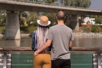 Rear view of couple standing near railings watching river — Stock Photo