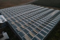 Aerial of structured glass roof of greenhouse in farmland. — Stock Photo