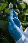 Close-up of scientist holding a syringe in green house — Stock Photo