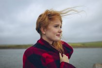 Thoughtful redhead woman standing in windy beach. — Stock Photo