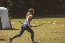 Adolescente correndo enquanto treinava tiro com arco no acampamento de inicialização na grama — Fotografia de Stock