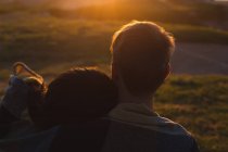 Романтична пара сидить на пляжі під час заходу сонця — стокове фото