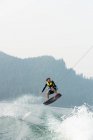 Male wakeboarder riding waves of woodland river — Stock Photo