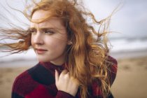 Thoughtful redhead woman standing in beach. — Stock Photo