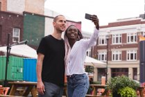 Smiling young couple taking selfie against buildings — Stock Photo