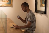 Чоловік використовує мобільний телефон, маючи каву в кафе — стокове фото