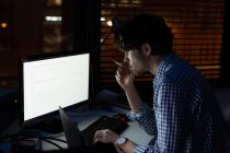 Nachdenkliche männliche Führungskraft, die nachts am Desktop-PC im Büro arbeitet — Stockfoto