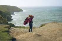 Rossa donna in piedi in spiaggia ventosa . — Foto stock