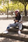 Молода жінка скейтбордистка використовує мобільний телефон у місті — стокове фото