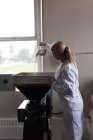Travailleur féminin mettant du blé dans la machine de concassage de blé à l'usine — Photo de stock