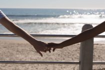 Пара держащихся за руки на набережной возле пляжа — стоковое фото