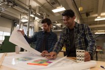 Two smart craftsmen working in workshop with blueprints — Stock Photo