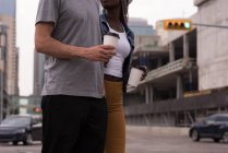 Mittelteil eines Paares mit Kaffeetassen, das auf der Straße spaziert — Stockfoto