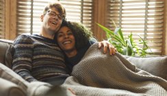 Couple relaxing under blanket in living room at home — Stock Photo