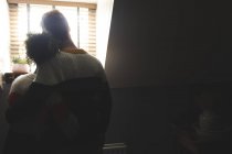 Vista trasera de la pareja abrazándose en casa con retroiluminación - foto de stock