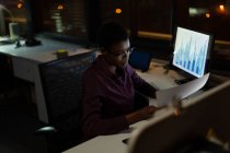 Female executive working at desk in office at night — Stock Photo