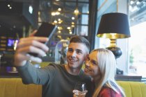 Primer plano de la pareja tomando selfie en el restaurante - foto de stock