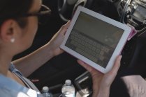 Крупним планом жінка використовує цифровий планшет в машині — стокове фото