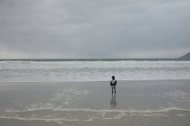 Вид ззаду дівчини, що стоїть на пляжі — стокове фото