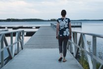 Rückansicht einer Frau, die auf Seebrücke geht — Stockfoto