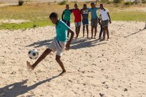 Мальчик играет в футбол на земле в солнечный день — стоковое фото