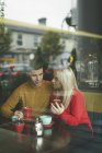 Молода пара обговорює на мобільному телефоні в кафе — стокове фото