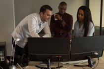 Виконавці обговорюють настільний комп'ютер за столом в офісі — стокове фото