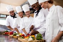 Head chef teaching his team to chopping vegetable in kitchen — Stock Photo