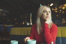 Thoughtful woman looking away in cafeteria — Stock Photo