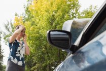 Frau telefoniert bei Autopanne an sonnigem Tag — Stockfoto