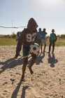 Niño jugando al fútbol en el suelo en un día soleado - foto de stock