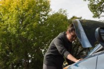 Жінка перевірки автомобіля під час розбивка на сонячний день — стокове фото