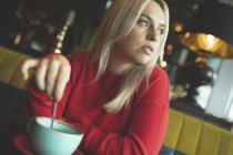 Frau schaut weg, während sie im Café Kaffee rührt — Stockfoto